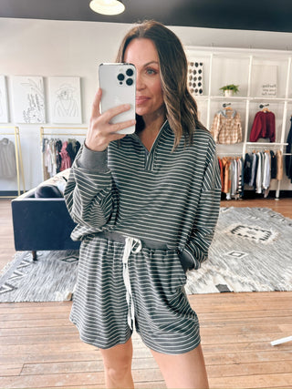 Woman taking a mirror selfie wearing a striped outfit in a clothing store.