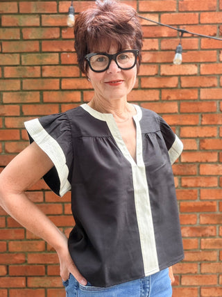 Amina Flutter Sleeve V-Neck Top - Black-Tops CasualAmina Flutter Sleeve V-Neck Top – Black | THML – VerClare Boutique-Shop the THML Amina Flutter Sleeve V-Neck Top in Black. Linen-viscose blend, flutter sleeves, contrast trim, V-neck, true-to-size fit. Sizes XS–L.-VerClare Boutique