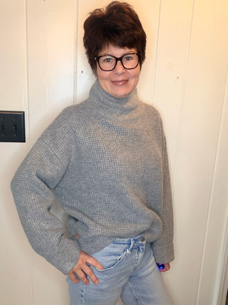 Lexi Waffle Knit Turtleneck Sweater-SweatersGrey Waffle Knit Turtleneck Sweater | VerClare Boutique-Shop the Lexi grey waffle knit turtleneck sweater, a cozy textured layer made with 50% recycled cotton. Available in sizes S/M and M/L.-VerClare Boutique