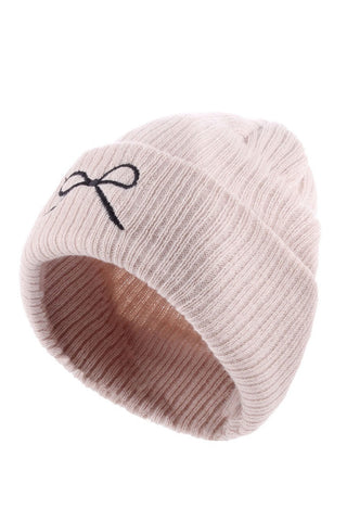 Beige knit beanie with a black bow on a white background